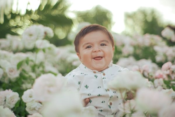 Bebé sentado entre flores sonriendo