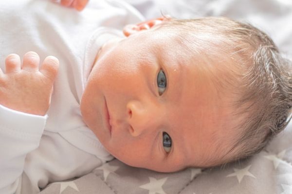 Bebé recién nacido mirando a cámara con mirada tierna