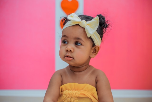 Niña con diadema y lazode perfil Niña pequeña con una diadema en la cabeza mirando de perfil