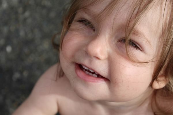 Primer plano de una niña pequeña que mira hacia arriba con cara feliz