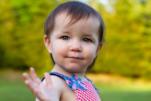 Niña morena de pelo corto y ojos verdes mirando a la cámara con expresión tierna