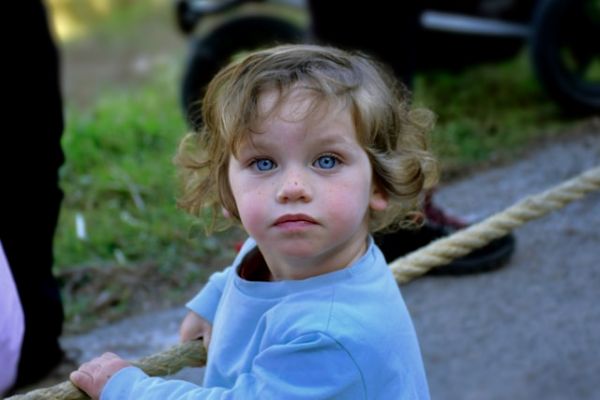 Niño de melana castaña agarrando una cuerda Niño de melena castaña rizada agarrando una cuerda y mirando a cámara