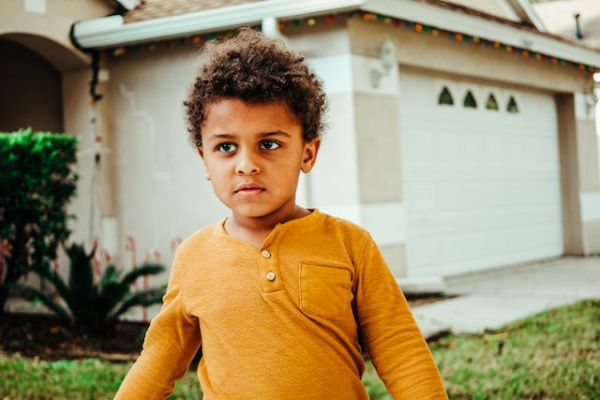 Niño moreno en el jardín de una casa Niño moreno caminando en el jardín de una casa