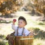 Niño con boina y camisa en el bosque, cogiendo una manzana