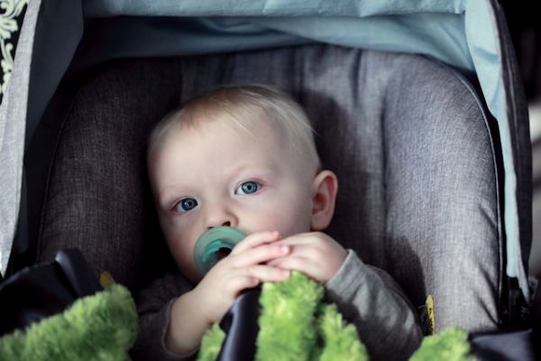 Bebe niño con chupete mirando a cámara Bebé niño con chupete sentado en un cochecito y mirando a cámara