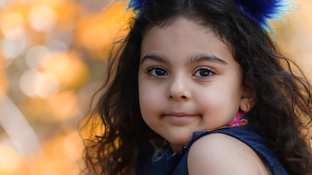 Primer plano de niña con larga melena rizada Niña morena de larga melena rizada mirando a cámara