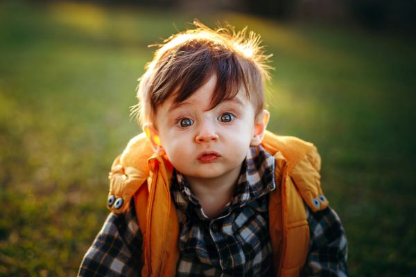 Niño con camisa de cuadros mirando a cámara con cara graciosa