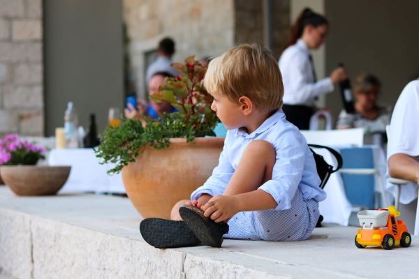 Niño con camisa y pantalones azules en un restaurante sentado de perfil