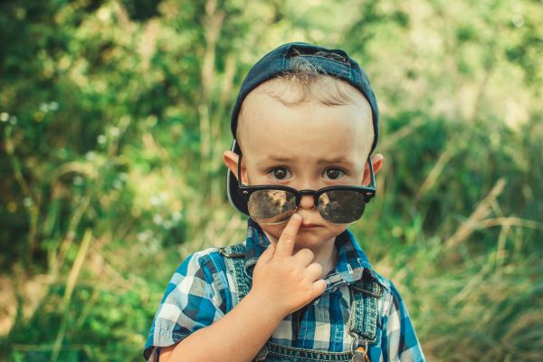 Niño con gorra y gafas de sol mirando a cámara