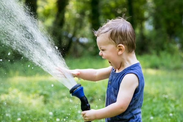 Niño riendo y jugando con agua al aire libre