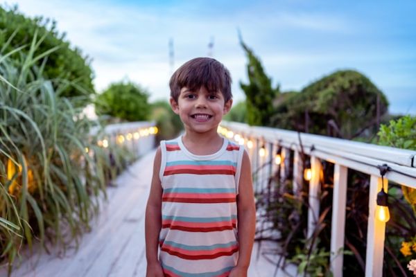 Niño en un puente sonriendo y mirando a cámara en un paisaje de verano