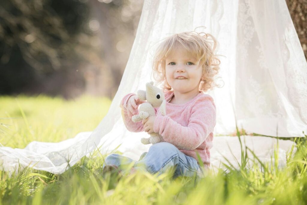 Niña jugando en el campo Niña en el campo sentada jugando con un peluche
