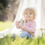 Niña sentada en el prado jugando con un peluche