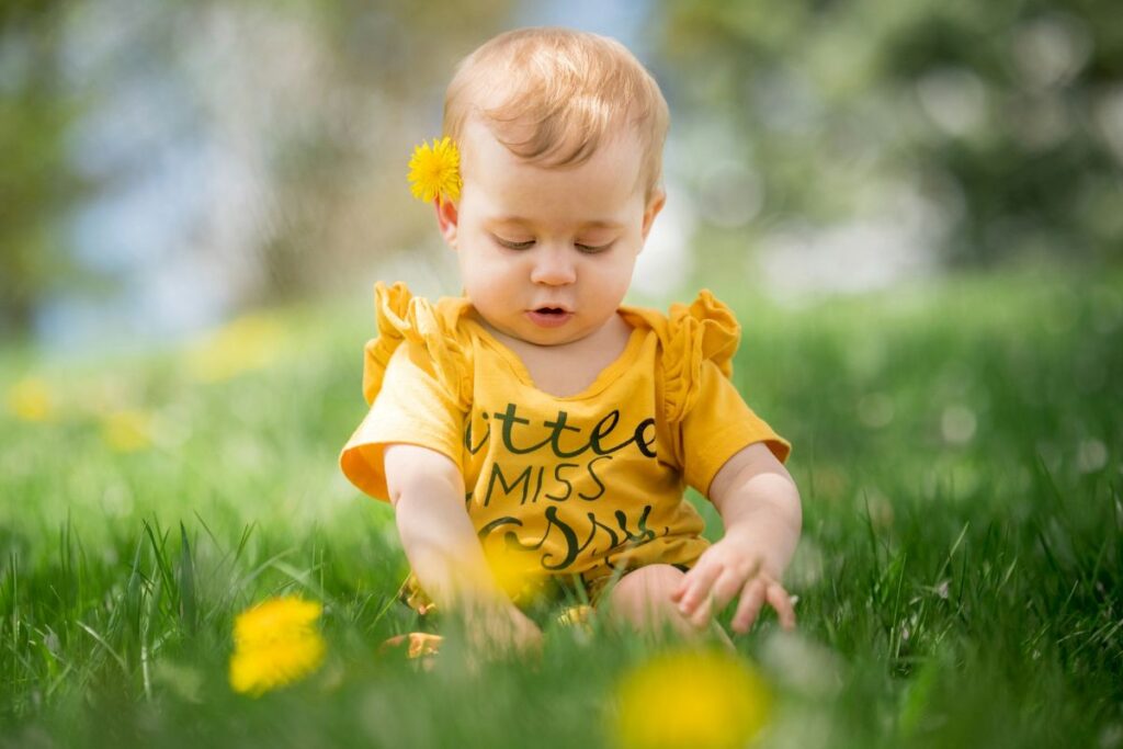 Niña sentada en la hierba jugando con flores
