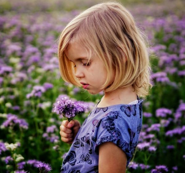 Niña de perfil sosteniendo un ramo de flores lilas