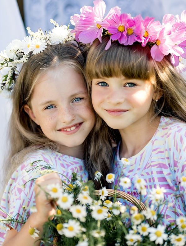 Dos niñas con coronas de flores sonriendo a cámara