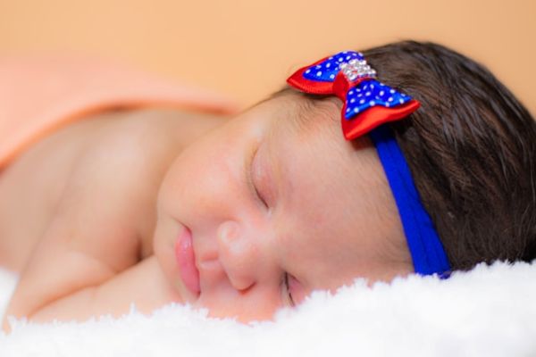 Bebé niña con diadema azul y roja dormida en un primer plano